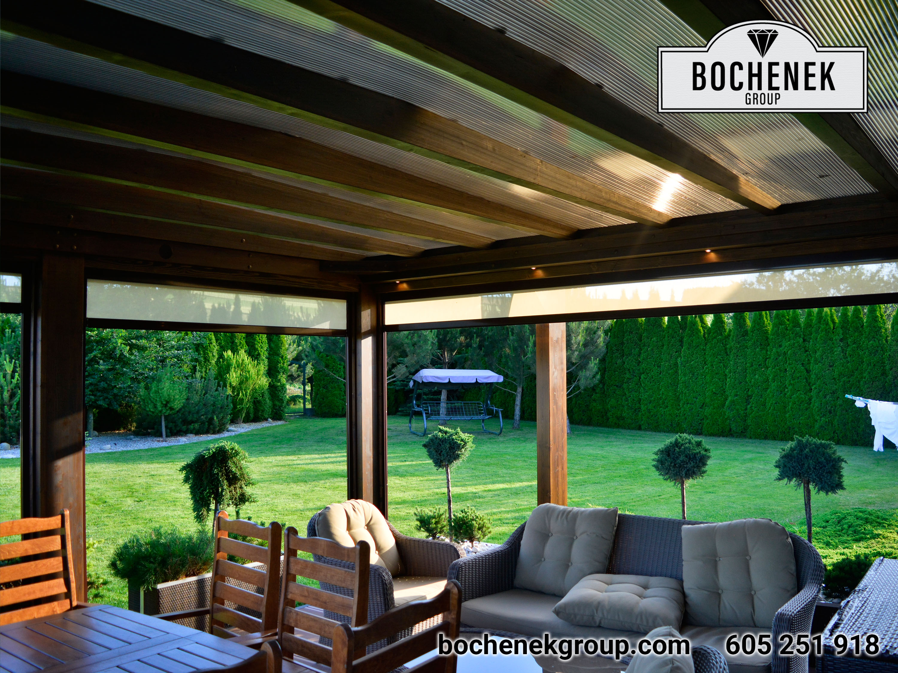 Zadaszone patio z biala sofa, lezakami i stolem do jedzenia pod drewniana pergola