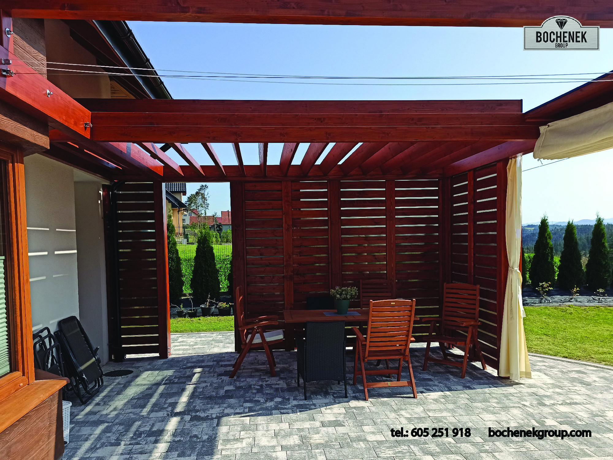 Drewniana pergola z azurowymi sciankami, stolem i krzeslami na przydomowym tarasie – realizacja Wenus